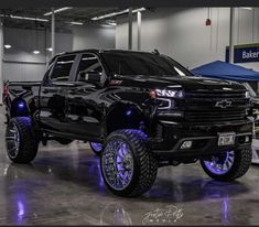 a black truck with blue lights on it's tires and rims in a showroom