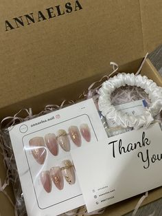 an open box with pink and gold nails in it's wrapper, next to a thank you sign