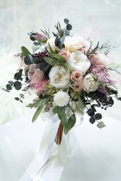 a bouquet of flowers on a table in front of a window with white and pink colors