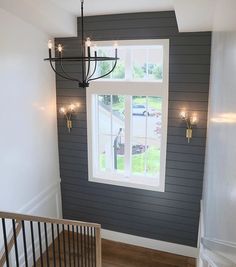 a chandelier hanging from the ceiling in a room with gray walls and wood flooring