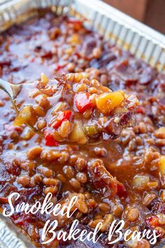 a spoon with some food in it on top of a tin foil pan filled with sauce