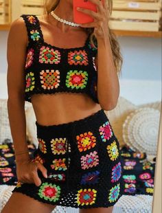 a woman taking a selfie while wearing a black crochet top and shorts