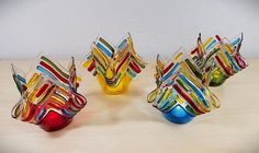 three colorful glass vases sitting on top of a wooden table next to each other