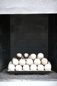 a bunch of white eggs sitting in a black box on the ground next to a brick wall