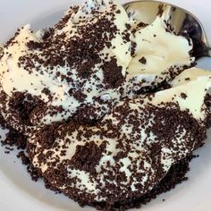 a white plate topped with cake and whipped cream on top of chocolate shavings