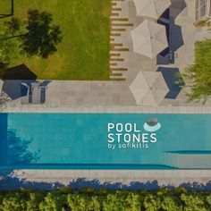 an aerial view of a swimming pool with umbrellas and chairs in the yard area