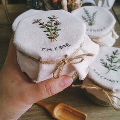 someone is holding three embroidered coasters in front of a wooden spoon and some other items