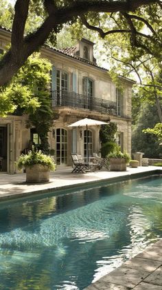 a house with a pool in front of it and an umbrella on the patio next to it