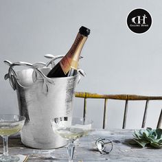 a bottle of wine in an ice bucket next to two glasses