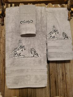 two towels with horses and jockeys on them are sitting on a wooden floor next to a towel rack