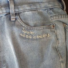 the back pocket of a pair of jeans with embroidered words on them, which reads spoiler we do not intend