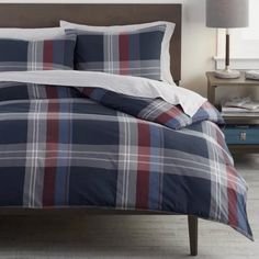 a bed with blue and red plaid comforter in a bedroom next to a night stand