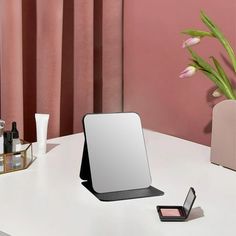 a white desk with a mirror, lipstick and other items sitting on top of it