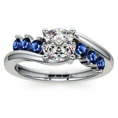 a white gold ring with blue sapphire stones on the sides and a center stone in the middle