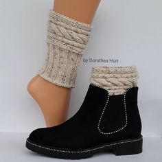 a pair of black and white boots with knitted socks on the toes, one is wearing