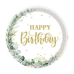 a paper plate with the words happy birthday in gold foil lettering on it, surrounded by greenery