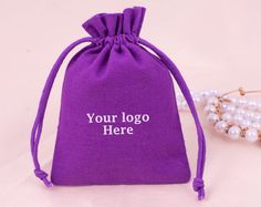 a purple bag sitting next to a pearl necklace