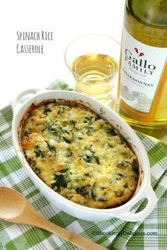 spinach rice casserole in a white dish next to a bottle of wine