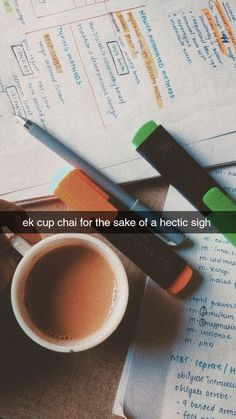 a cup of coffee sitting on top of an open book next to a pen and calculator