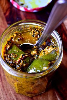 a jar filled with food sitting on top of a wooden table next to a spoon