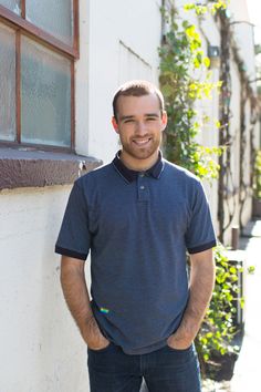 a man standing in front of a building with his hands on his hips and smiling