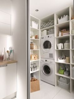 a washer and dryer in a small room with shelves on the wall next to each other