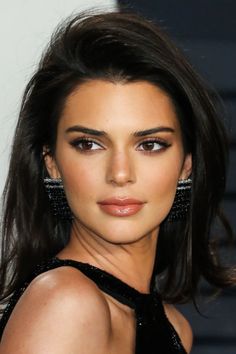 a close up of a person with long dark hair and earrings on her head, wearing a black dress