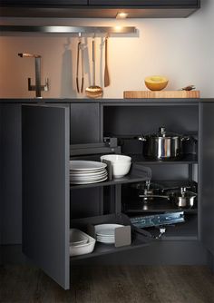 an open cabinet in a kitchen with pots and pans