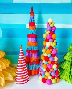 colorful paper christmas trees are lined up against a blue wall