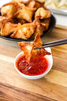 some food is on a plate with chopsticks and sauce in a small bowl