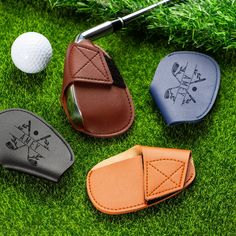 three golf club covers and a putter's mitt on the grass next to a golf ball