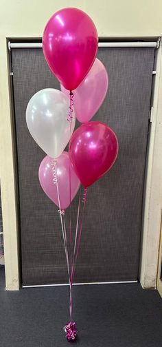 some pink and white balloons in front of a gray door with the words happy birthday on it