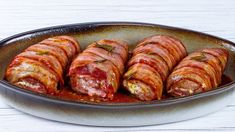 sausage wrapped in bacon and marinara sauce on a platter, ready to be eaten