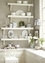 the shelves in this kitchen are filled with plates and bowls, vases and flowers