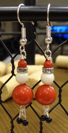 red and white beaded earrings hanging from a chain link fence