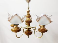 a chandelier with three lights hanging from it's sides and two lamps on each side