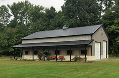 a small house with a metal roof in the middle of a grassy field next to trees