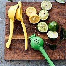 a cutting board with lemons, limes and a green grater on it