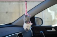 two crocheted mice hanging from a car's dash board ornament