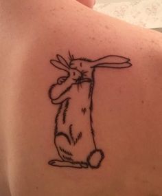 a rabbit tattoo on the back of a woman's upper arm, with one hand in the air