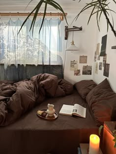 an unmade bed in a bedroom with a book and coffee cup on the table