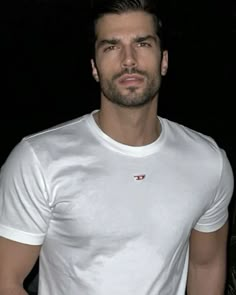 a man wearing a white shirt standing in the dark