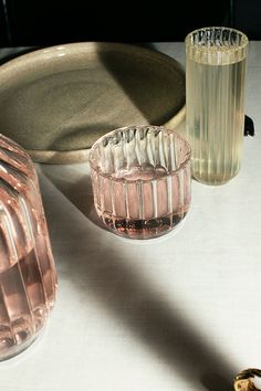 three glass vases sitting on top of a white table next to plates and glasses