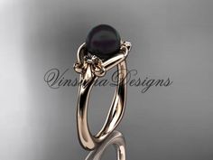 a yellow gold ring with an oval black pearl and flower design on the side, set in