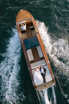 a bride and groom are on the back of a small boat in the middle of the water