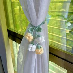 a curtain with flowers hanging from it in front of a window