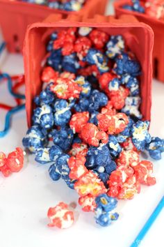 red, white and blue popcorn is spilled out of a container