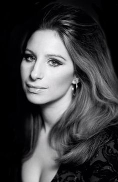 a black and white photo of a woman with long hair wearing large hoop earrings, looking at the camera