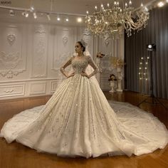 a woman in a wedding dress standing on a wooden floor with chandelier above her