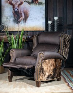 a living room with a cow print on the wall next to a chair and plant